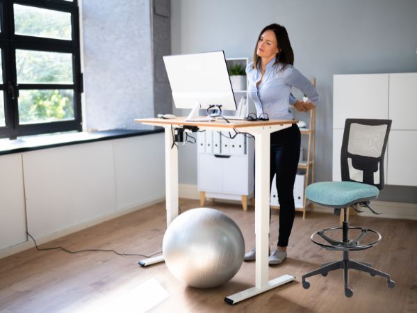  This photo is  an employee using a sit-stand desk and the Team Air Drafter Chair.
