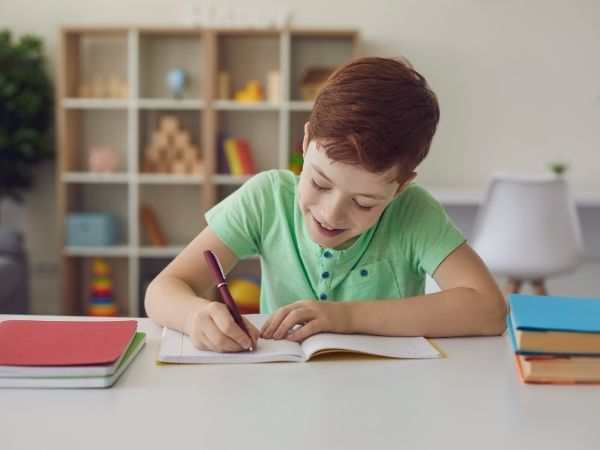 Photo of boy happily working on his new study desk, the Perfect Back to School Workspace.